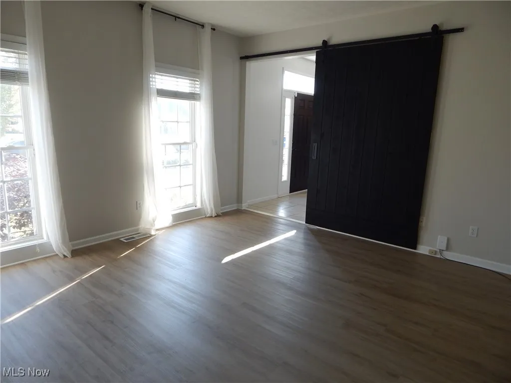 Empty room with a barn door and wood finished floors