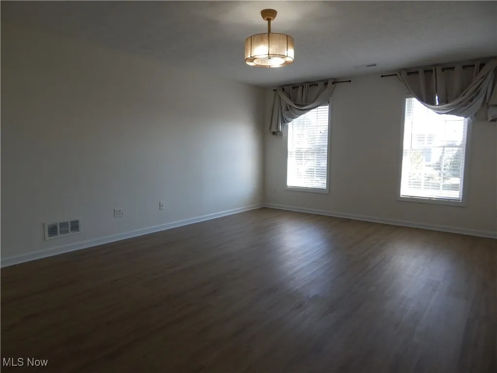 Unfurnished room with dark wood-style floors and baseboards