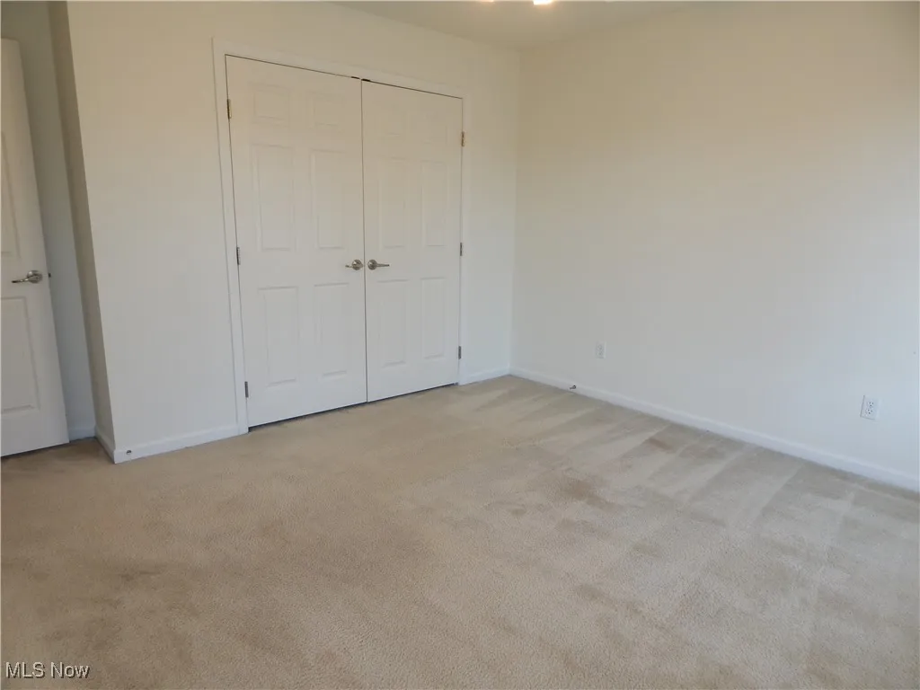 Unfurnished bedroom with light carpet and a closet