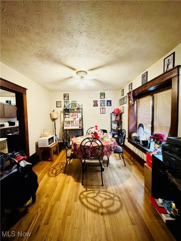 Dining area featuring a textured ceiling, light wood-style flooring, and a ceiling fan