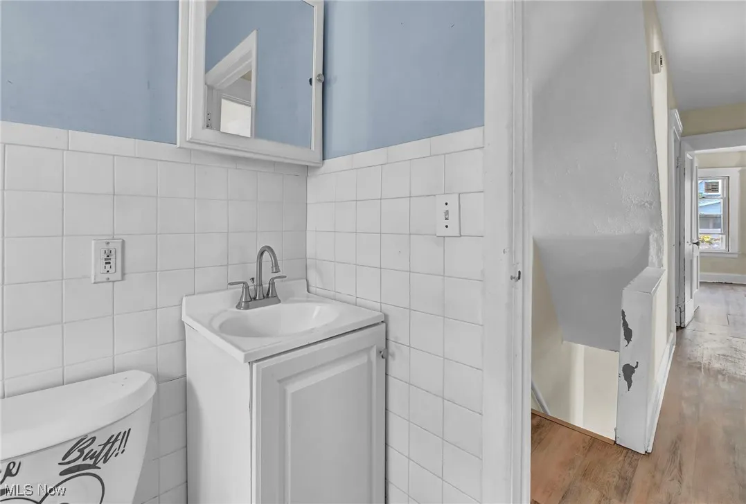 Bathroom featuring vanity, wood finished floors, and tile walls