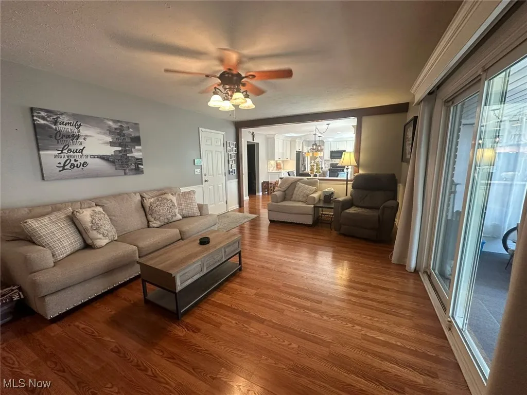 Living room featuring wood finished floors, a ceiling fan, and a textured ceiling