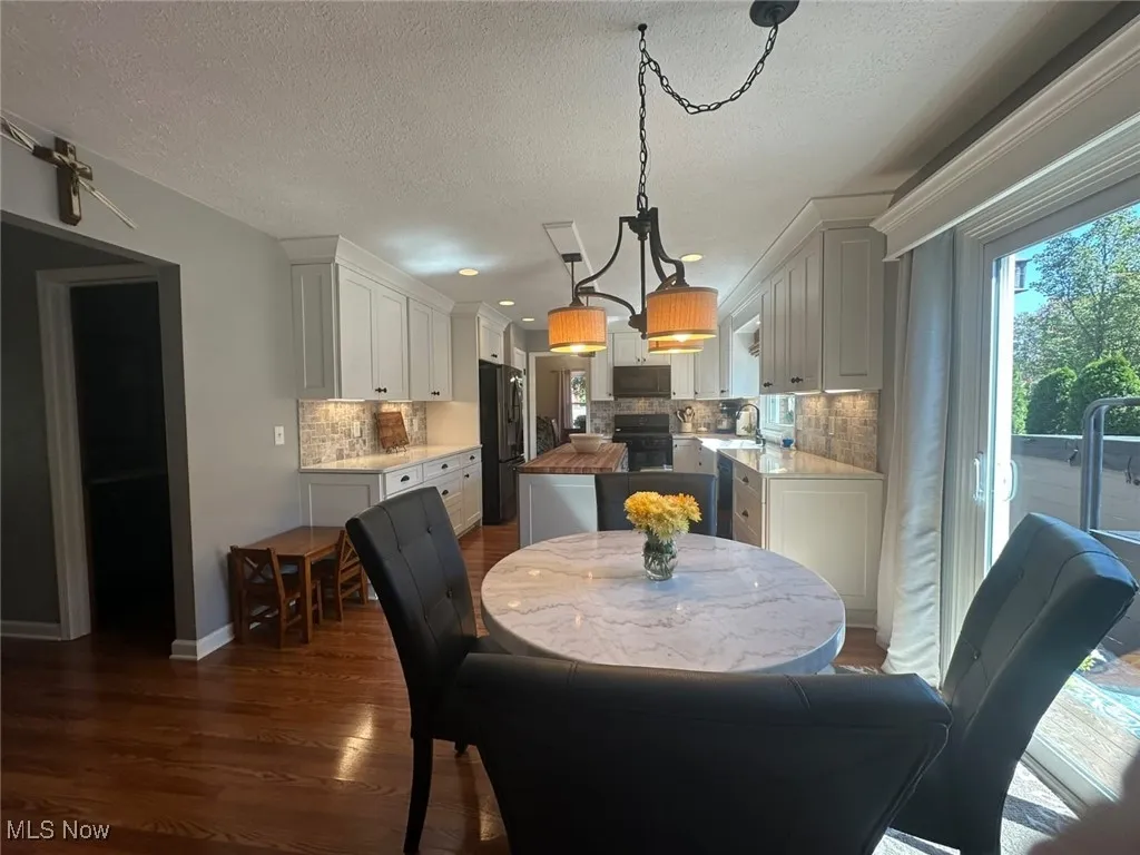 Dining room with dark wood finished floors, a textured ceiling, and recessed lighting