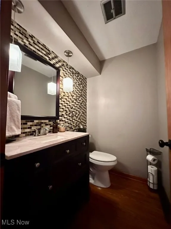 Bathroom featuring decorative backsplash, dark wood-style flooring, and vanity