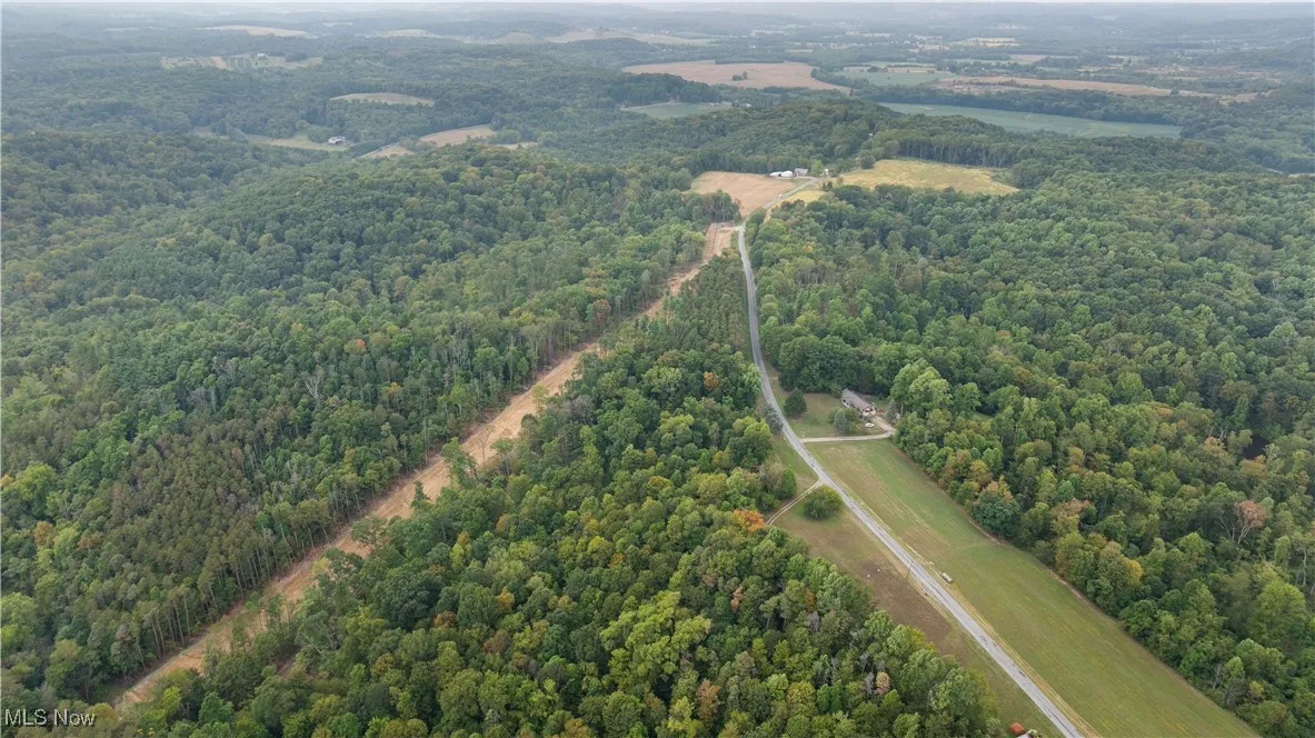 Aerial view of property and surrounding area featuring a forest