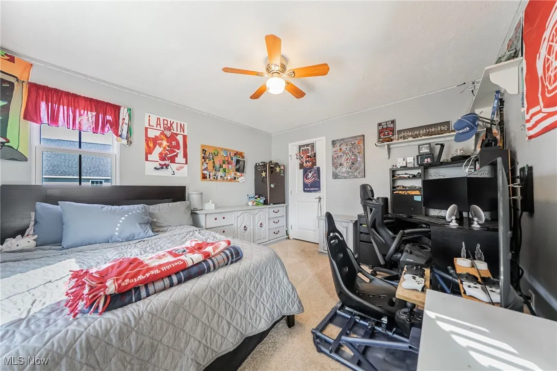 Bedroom with light carpet, a desk, and ceiling fan