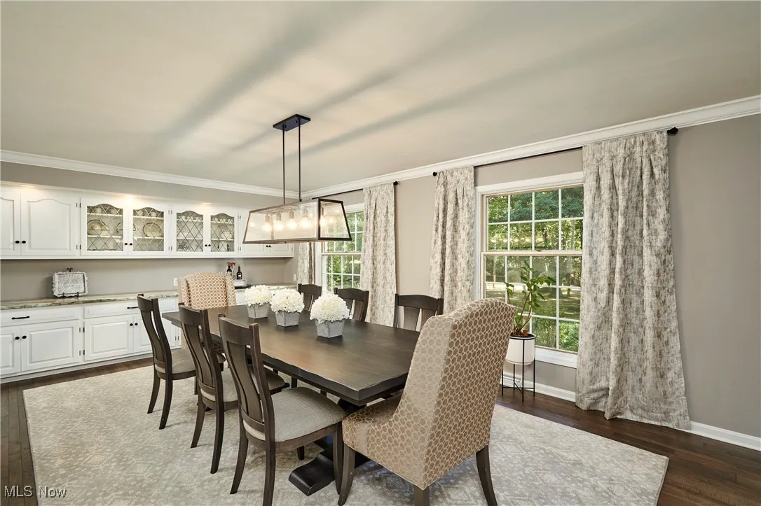 Dining space with crown molding and dark wood-style flooring