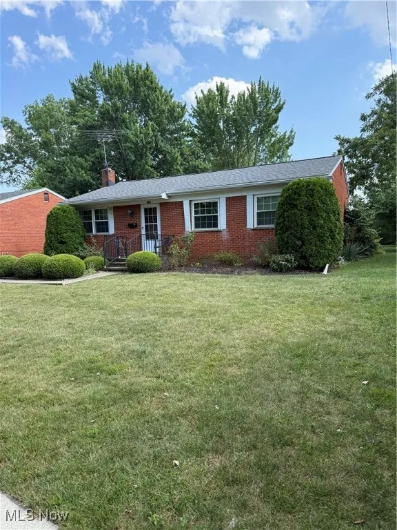 Single story home with brick siding, a chimney, and a front lawn