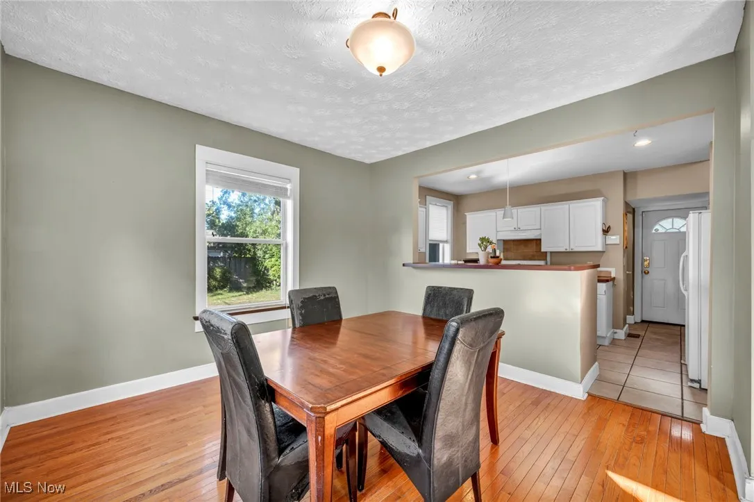 Dining area with healthy amount of natural light, light wood-style floors, and a textured ceiling