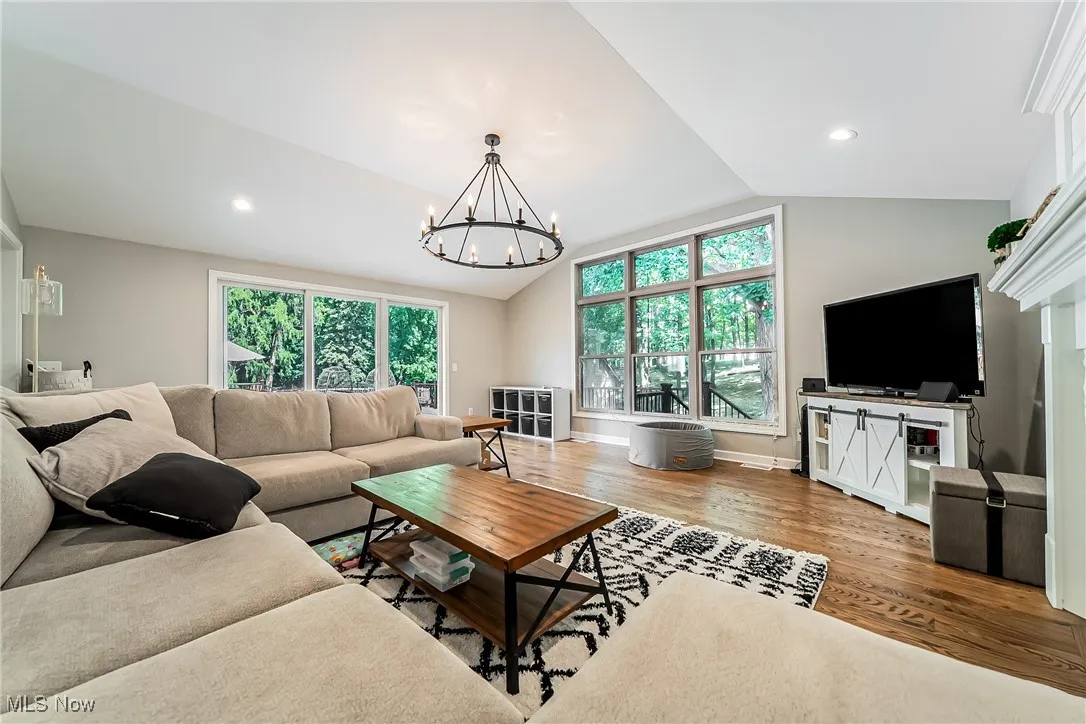 Living room featuring wood finished floors, lofted ceiling, a chandelier, recessed lighting, and a fireplace