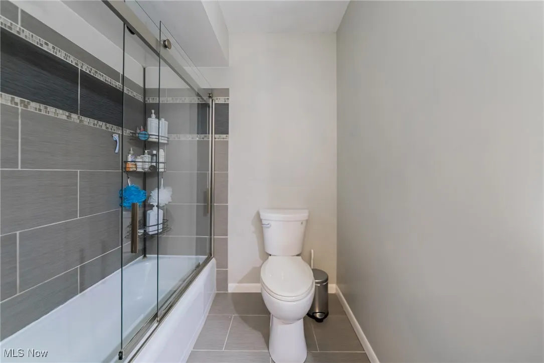 Bathroom featuring enclosed tub / shower combo and light tile patterned floors