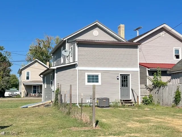Back of house featuring a lawn, entry steps, and a chimney