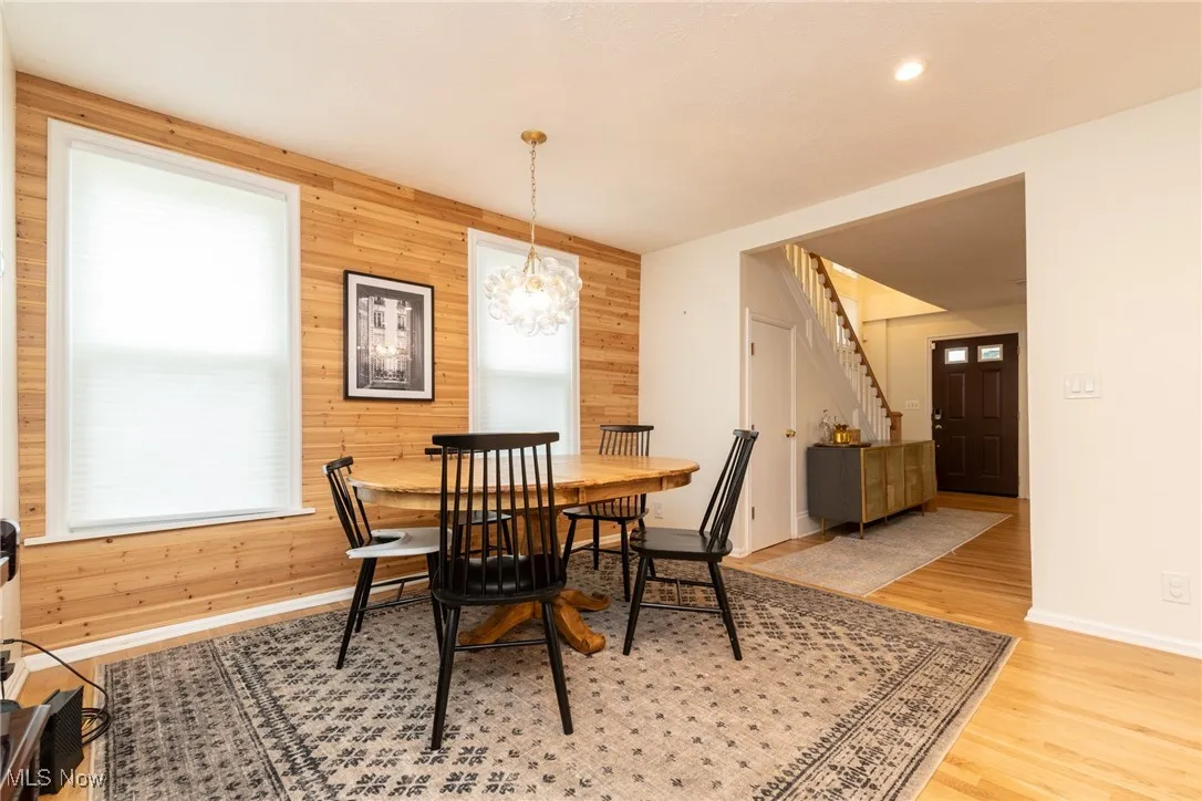 Dining space with wood walls, stairs, light wood finished floors, and a chandelier