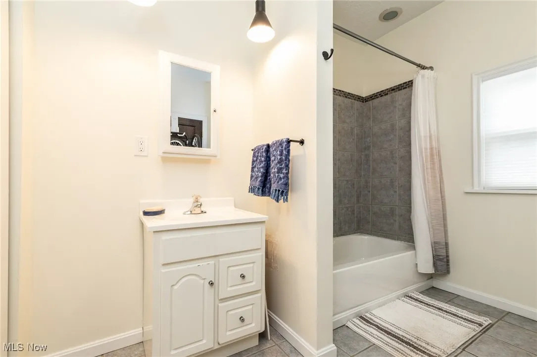 Full bathroom featuring shower / bath combo with shower curtain, vanity, and light tile patterned floors
