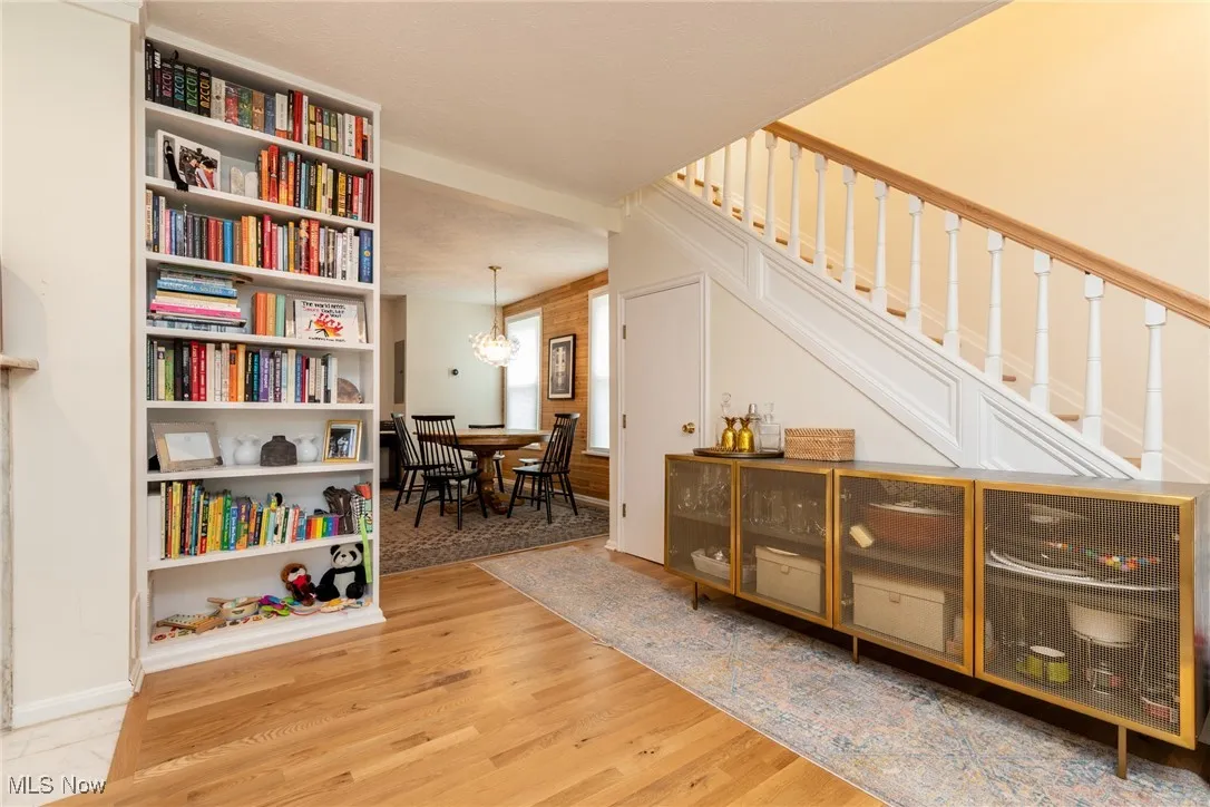 Living area featuring light wood finished floors, a chandelier, and stairs