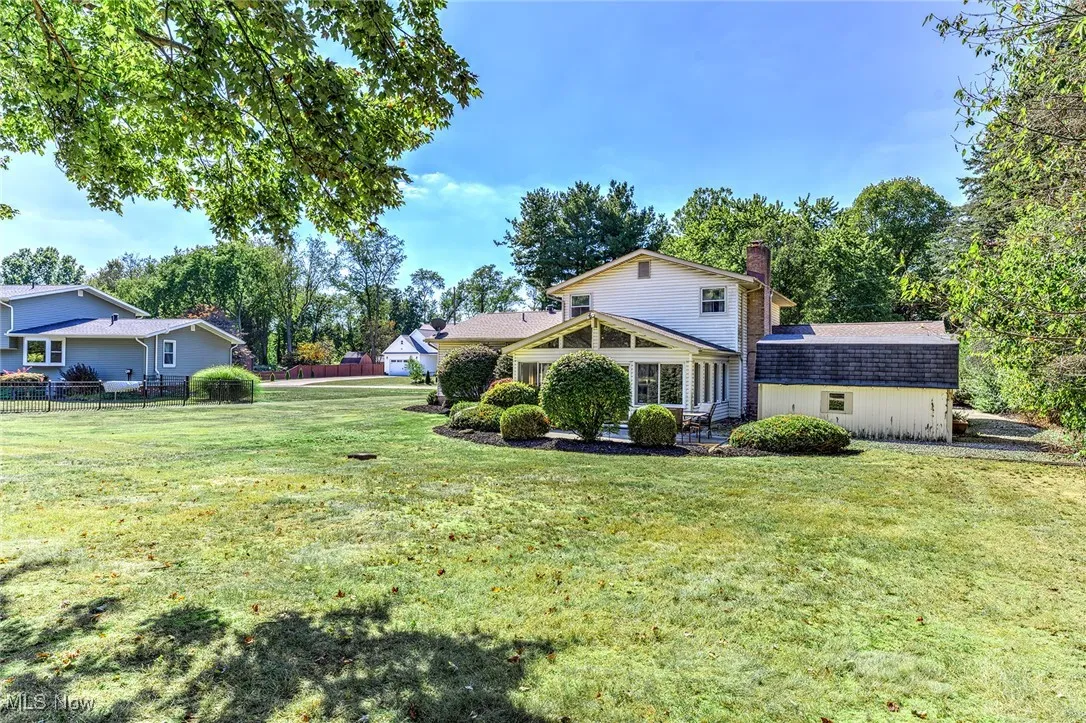 Rear view of property featuring a chimney, view of wooded area, and a shingled roof
