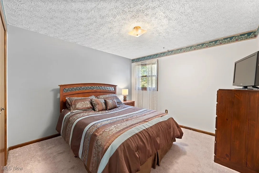 Bedroom with light colored carpet and a textured ceiling