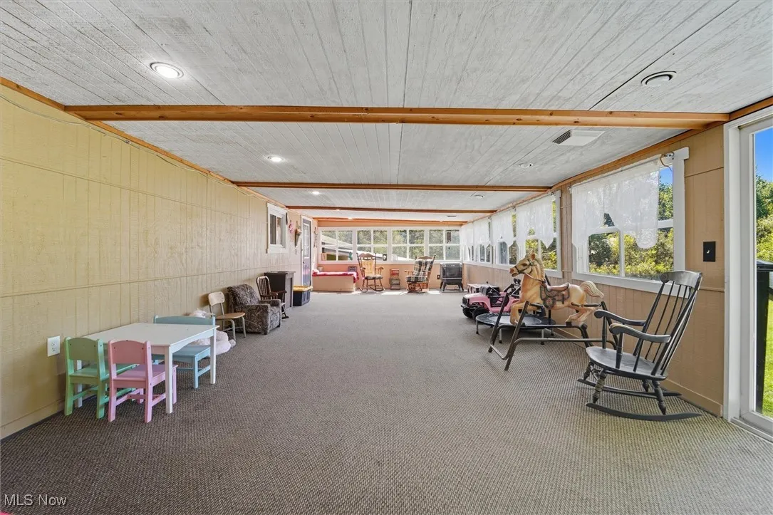 Sunroom / solarium with wood walls, carpet, a wood ceiling with exposed beams, and recessed lighting