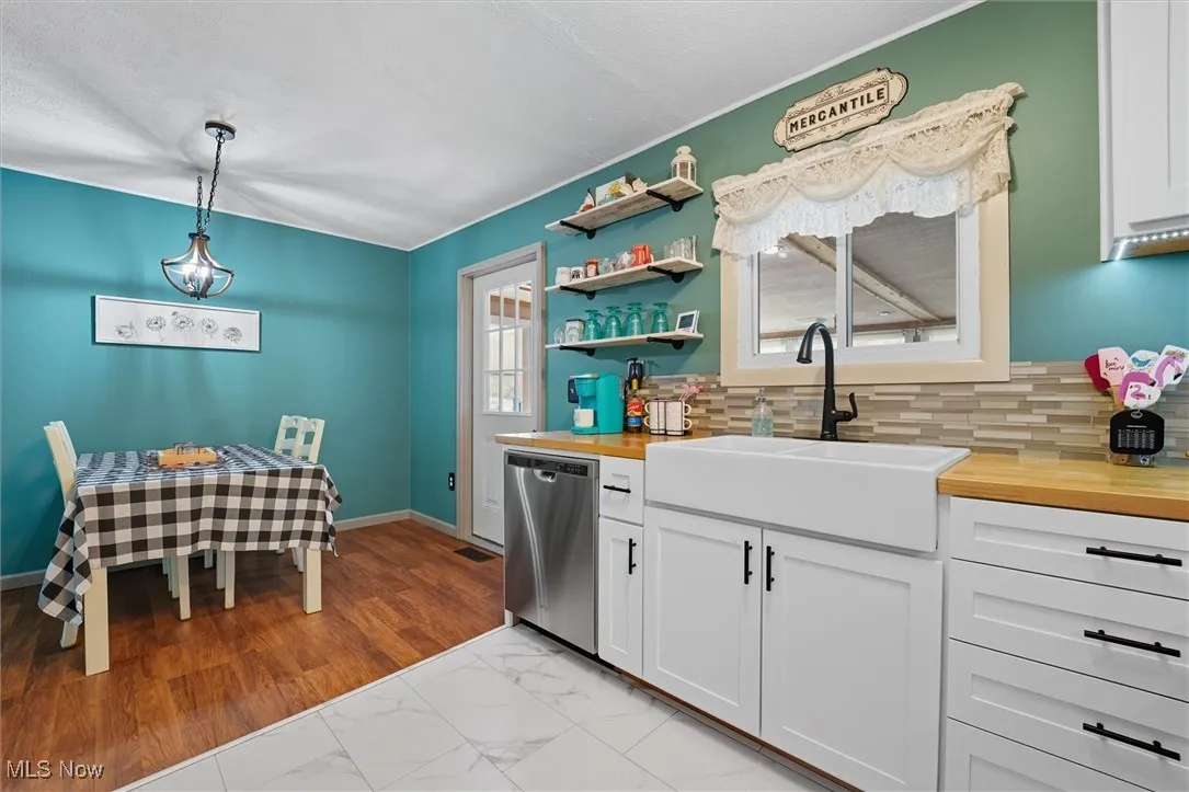Kitchen with wooden counters, white cabinetry, dishwasher, and light marble finish floors