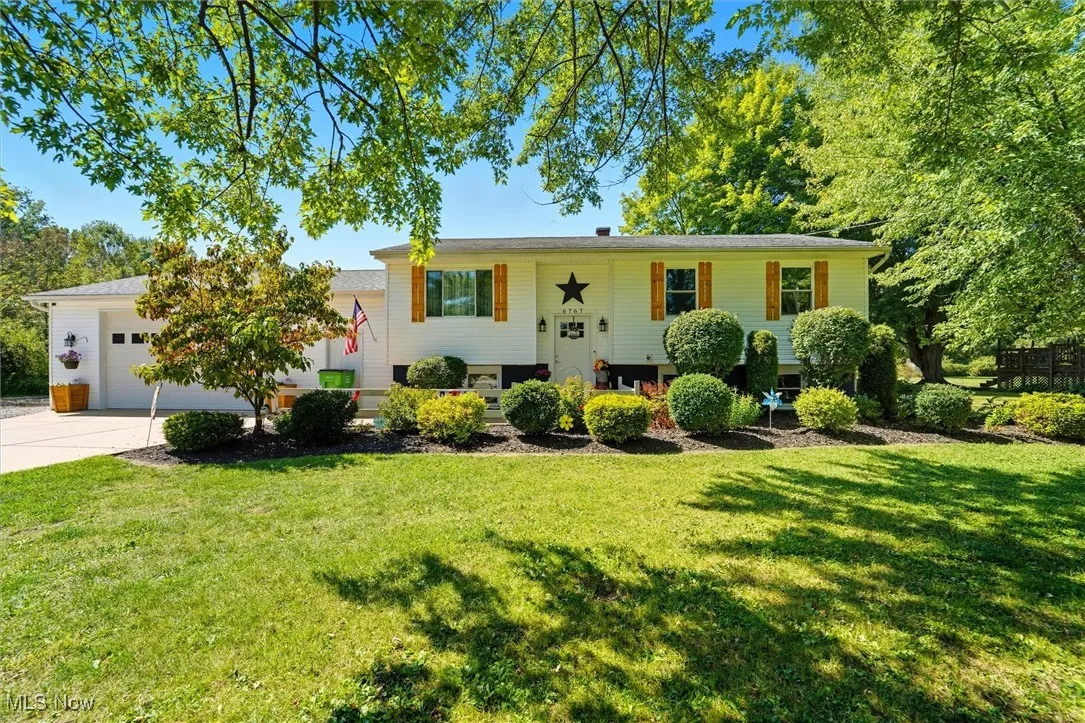 Bi-level home with concrete driveway, a front yard, and an attached garage