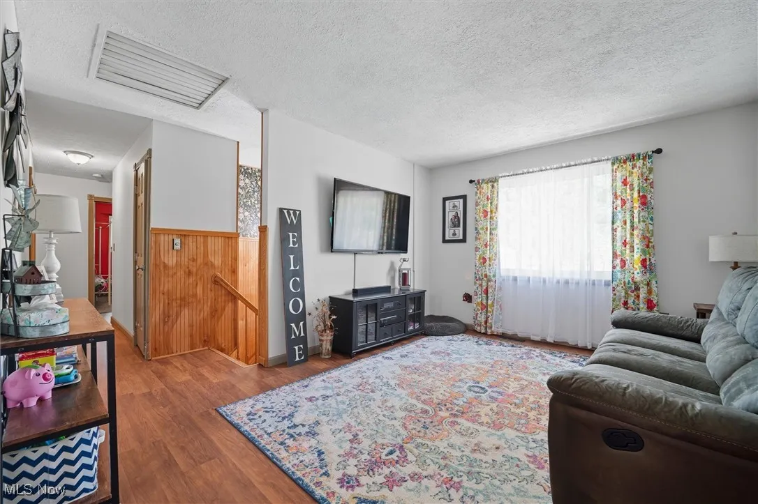 Living area with a textured ceiling, wood finished floors, and wood walls