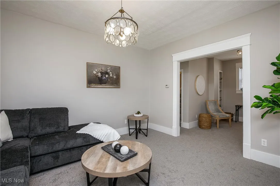 Carpeted living area with a chandelier and a textured ceiling
