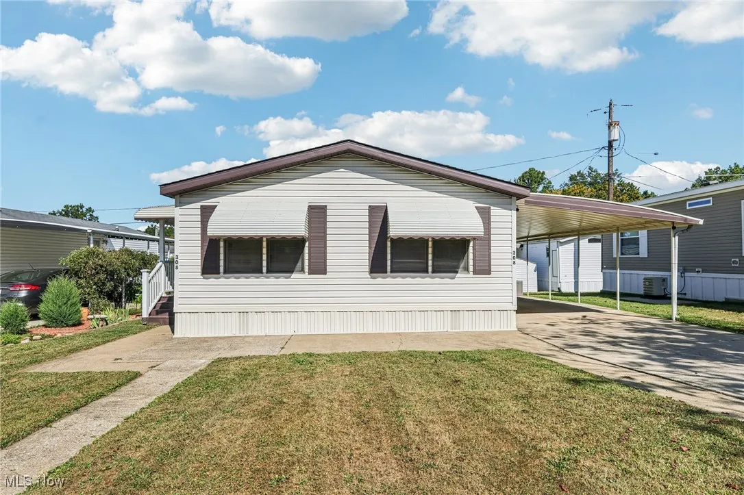 View of front of house with a front yard, driveway, and a carport