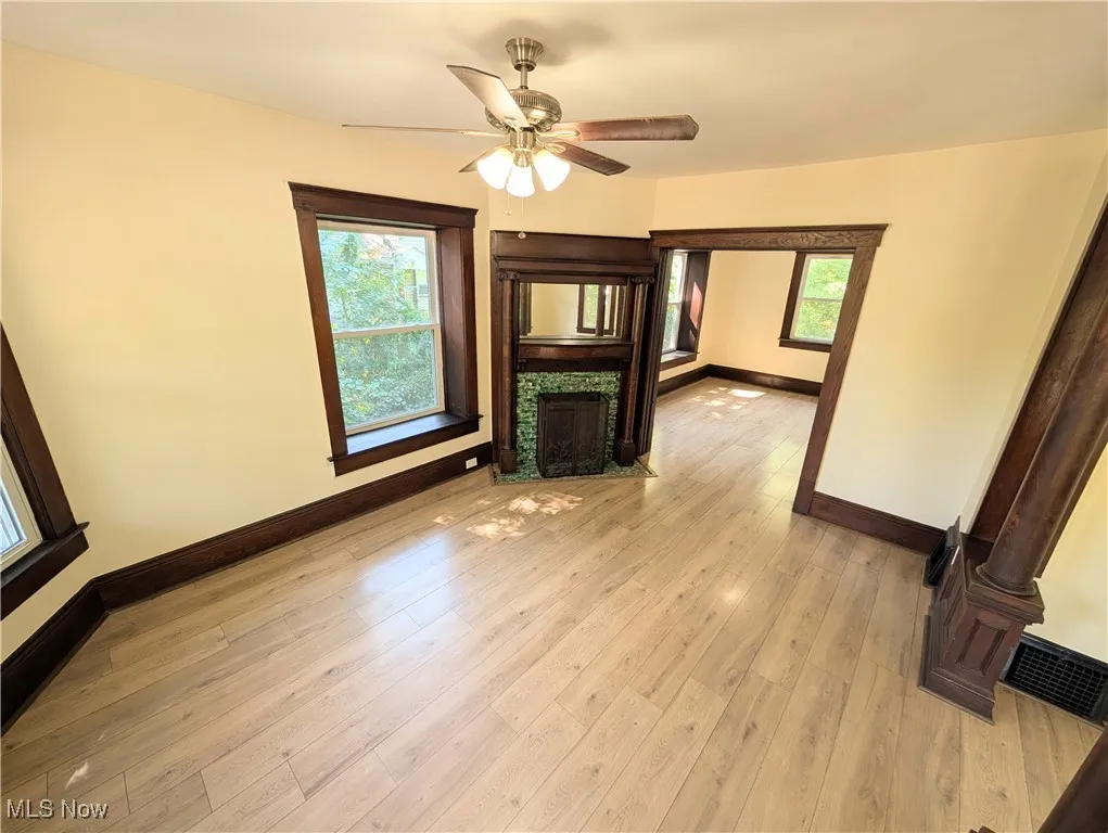 Unfurnished living room featuring light wood-style floors, healthy amount of natural light, a tiled fireplace, and a ceiling fan