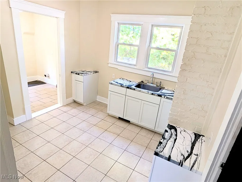 Kitchen with light tile patterned floors and white cabinetry
