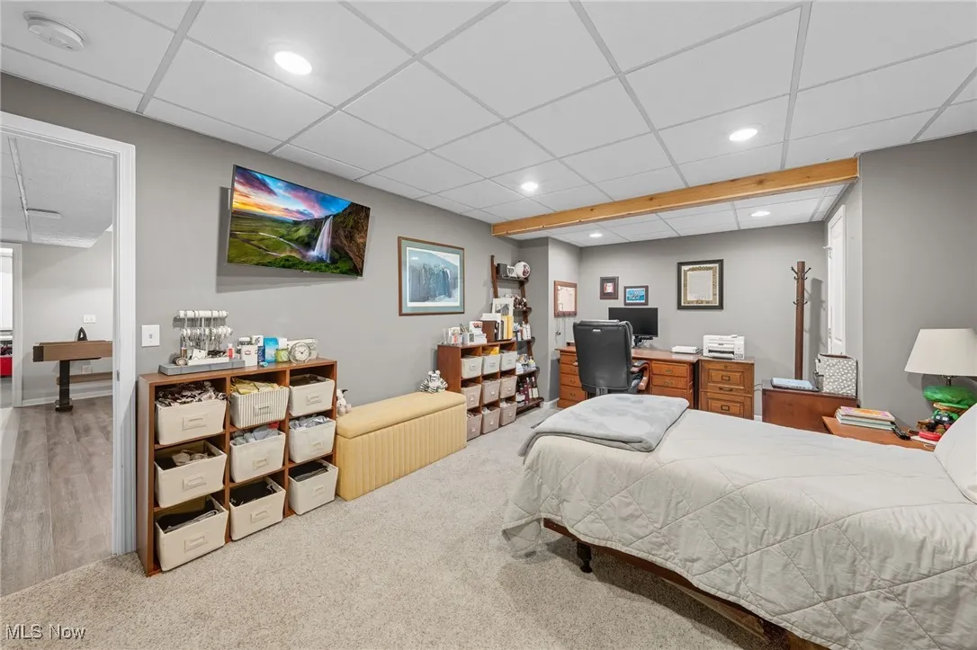 Carpeted bedroom featuring a paneled ceiling, recessed lighting, and an office area