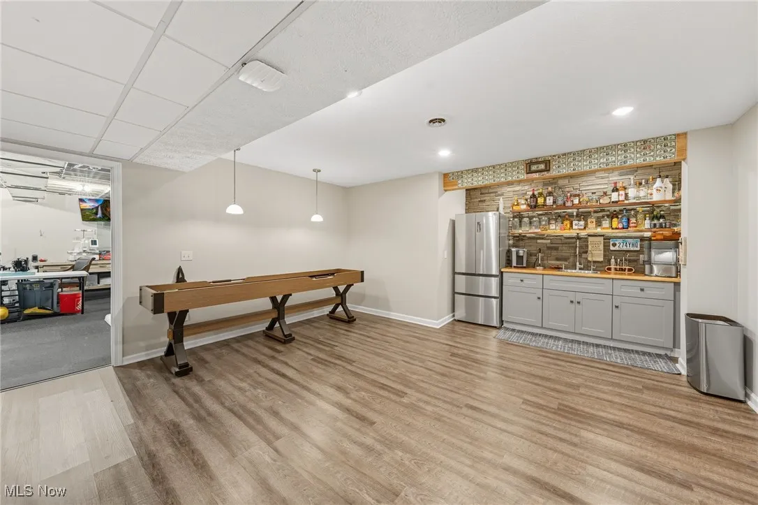 Indoor wet bar with pendant lighting, freestanding refrigerator, light wood-style flooring, open shelves, and pool table