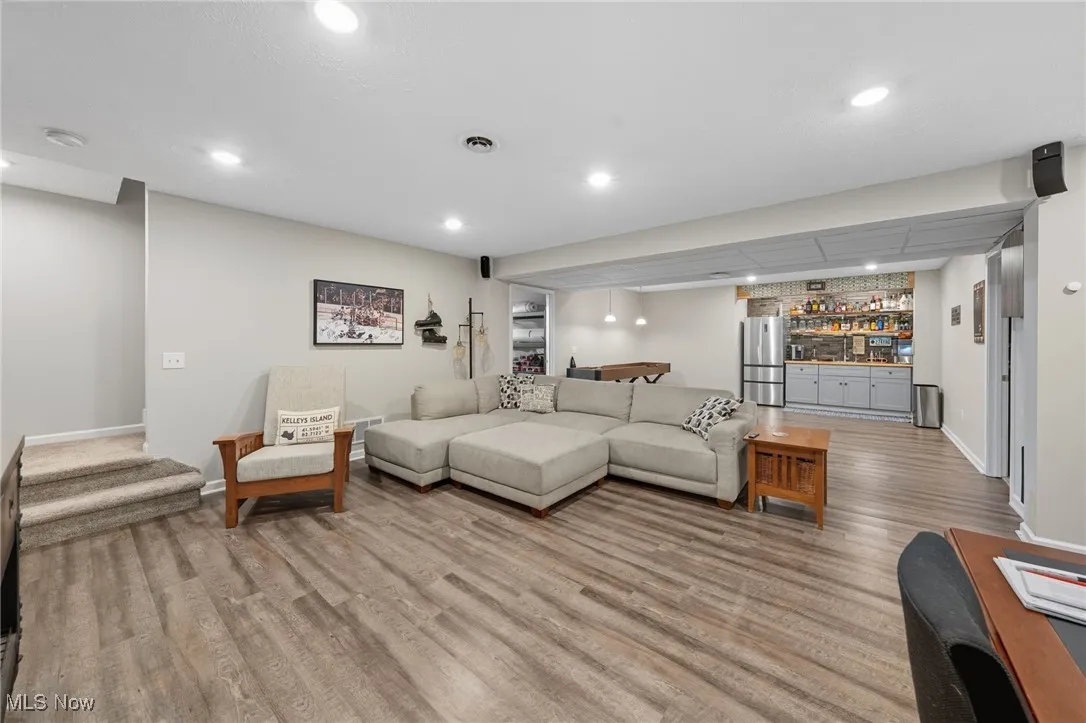 Living room featuring stairway, bar area, recessed lighting, and light wood-type flooring