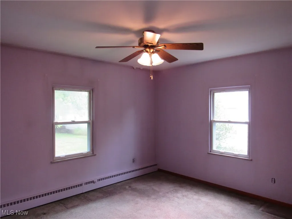 Unfurnished room featuring baseboard heating, carpet, and ceiling fan