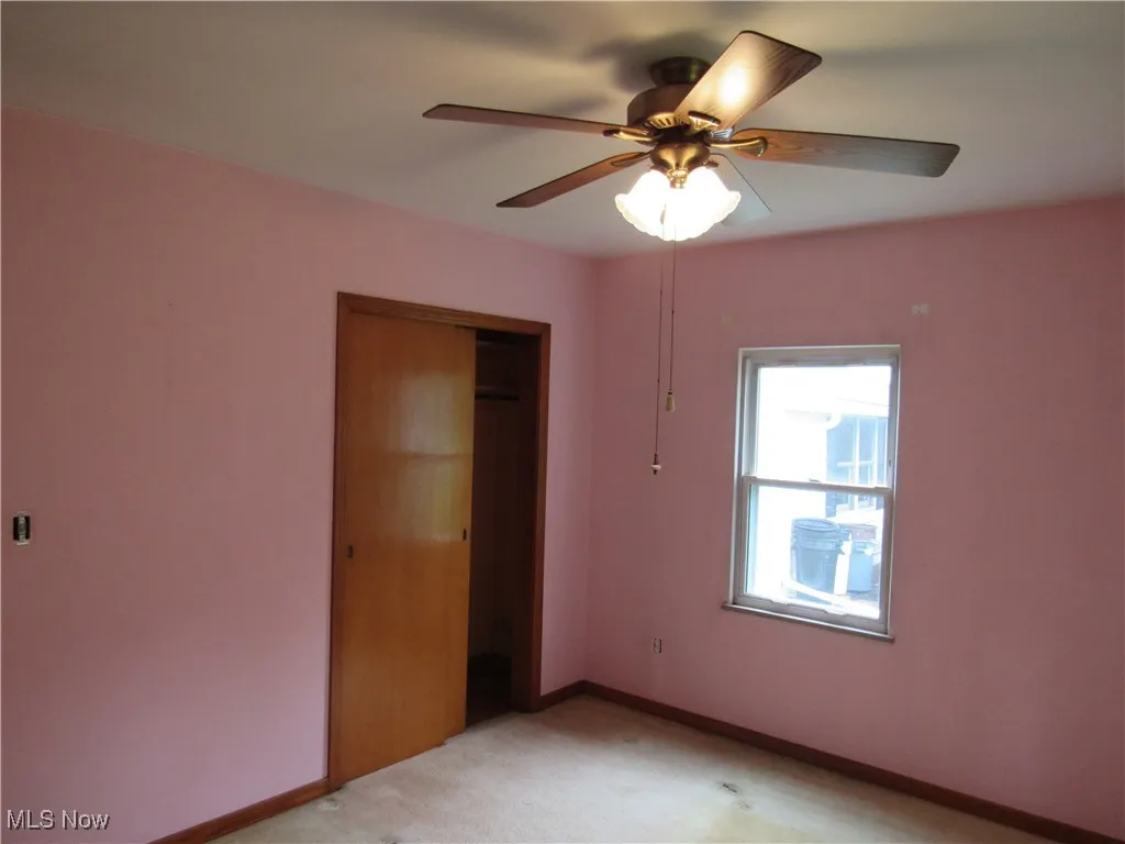 Unfurnished bedroom with carpet, a closet, and a ceiling fan