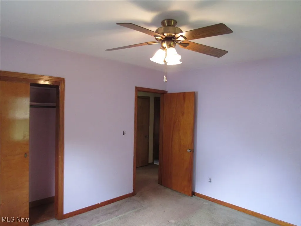 Unfurnished bedroom with light carpet, a ceiling fan, and a closet