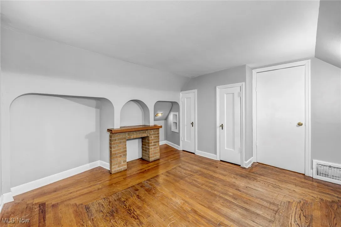 Unfurnished living room featuring vaulted ceiling and hardwood / wood-style flooring