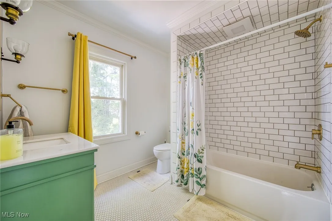 Bathroom featuring shower / bath combo with shower curtain, vanity, and crown molding