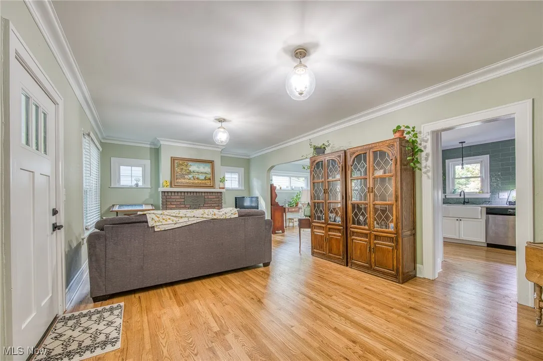 Living area featuring ornamental molding, light wood-type flooring, plenty of natural light, and arched walkways