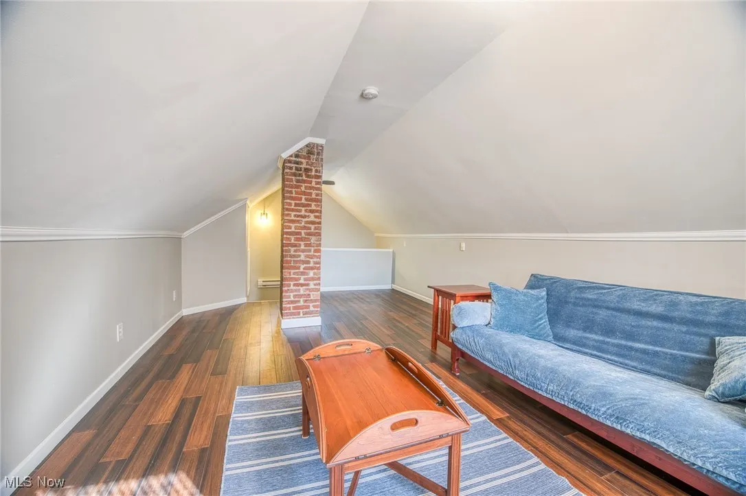 Additional living space featuring dark wood-style floors and vaulted ceiling
