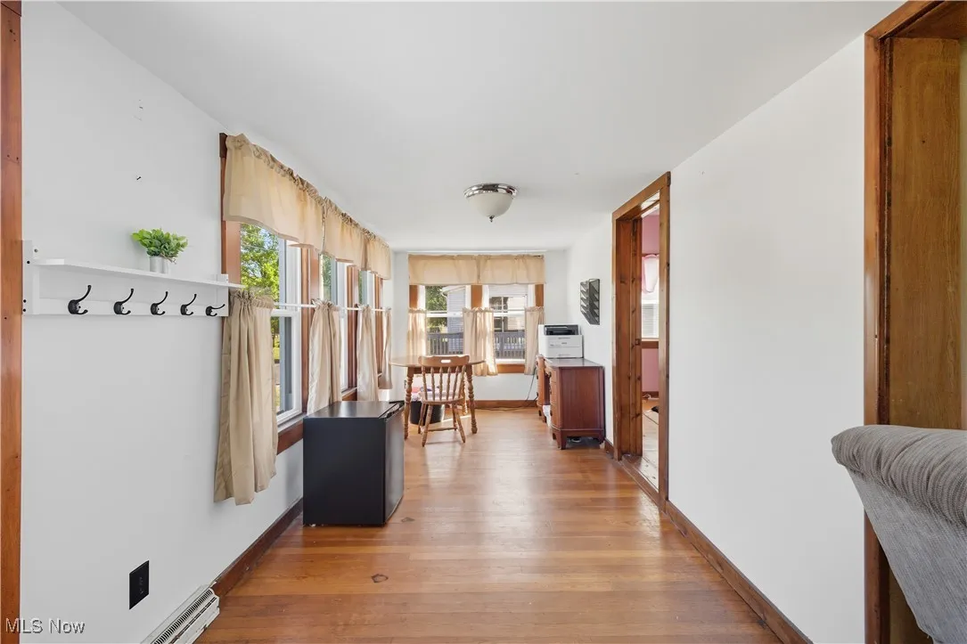 Hallway featuring light wood finished floors and a baseboard heating unit