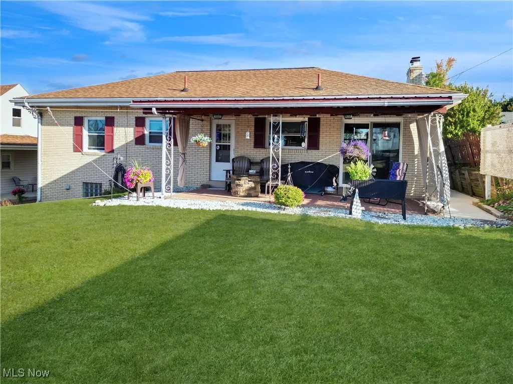 Rear view of house featuring a patio, a chimney, a yard, and brick siding