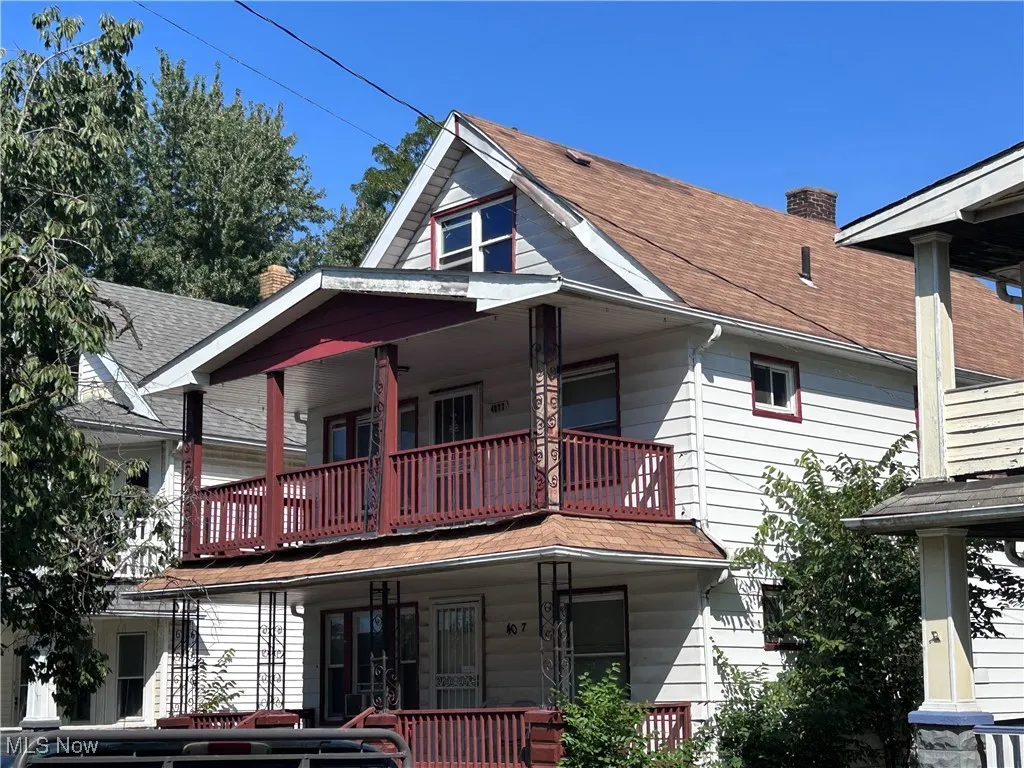 View of front facade featuring a porch, a chimney, and roof with shingles