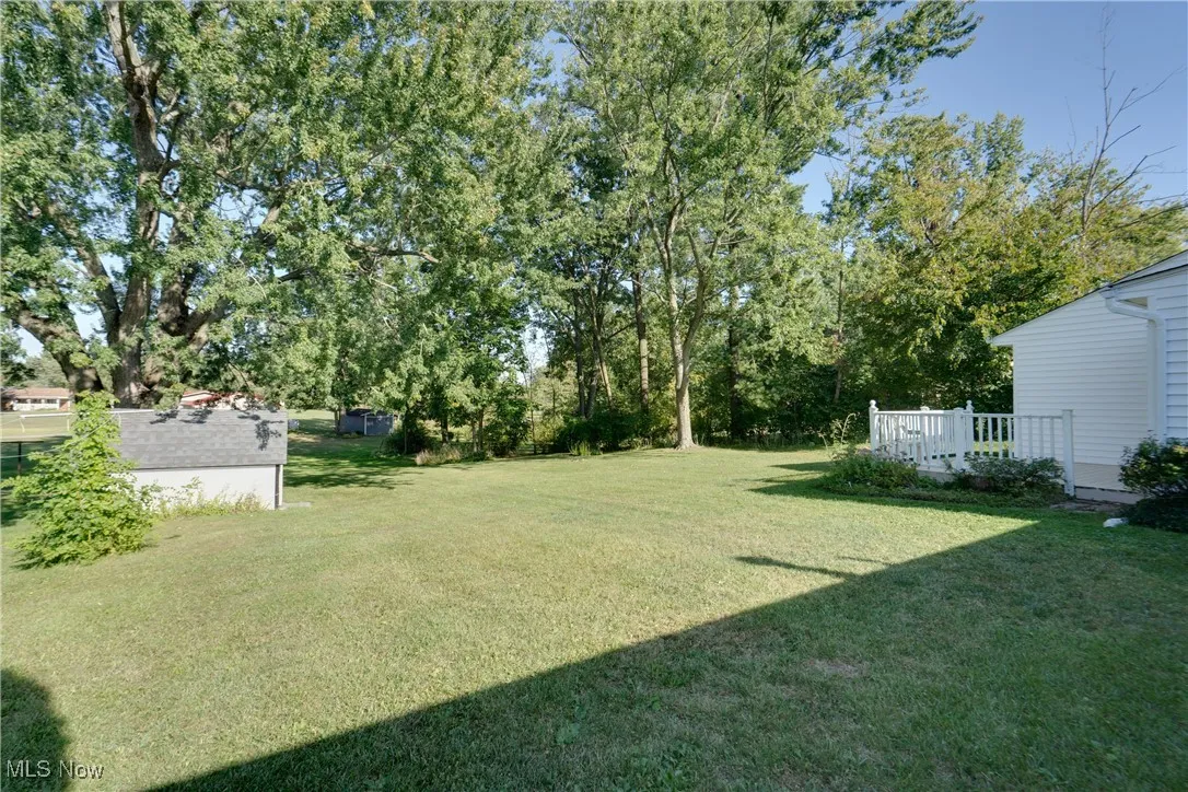 View of grassy yard with a deck and view of scattered trees