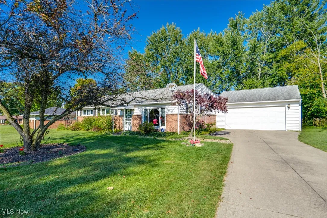 Single story home featuring a front lawn, brick siding, driveway, and an attached garage
