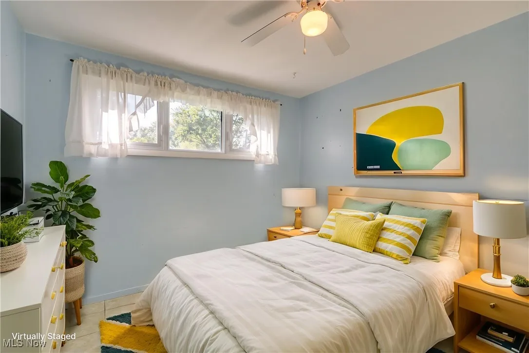 Tiled bedroom with a ceiling fan and baseboards