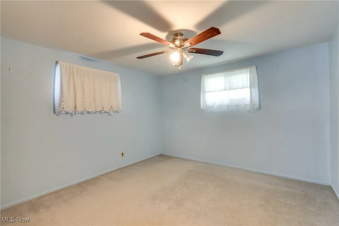Empty room featuring light carpet and a ceiling fan