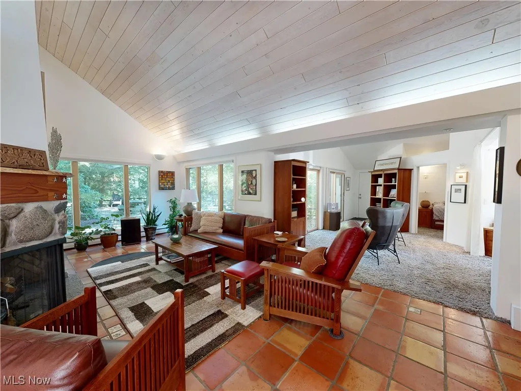 Living area with wooden ceiling, light colored carpet, a multi sided fireplace, high vaulted ceiling, and light tile patterned floors
