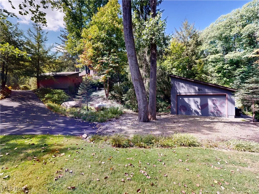 View of green lawn with an outdoor structure and a garage