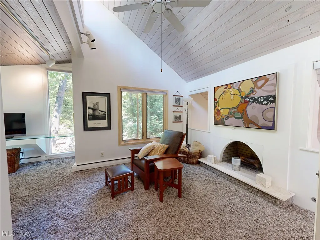 Living area with wood ceiling, carpet, a baseboard radiator, high vaulted ceiling, and ceiling fan