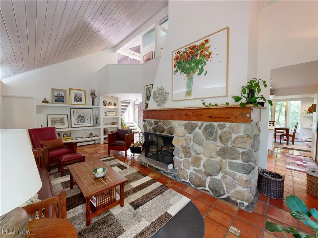 Living room with high vaulted ceiling, a fireplace, and tile patterned floors